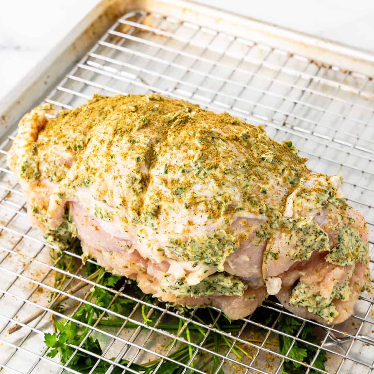 Boneless turkey breast with herb butter on a roasting pan.